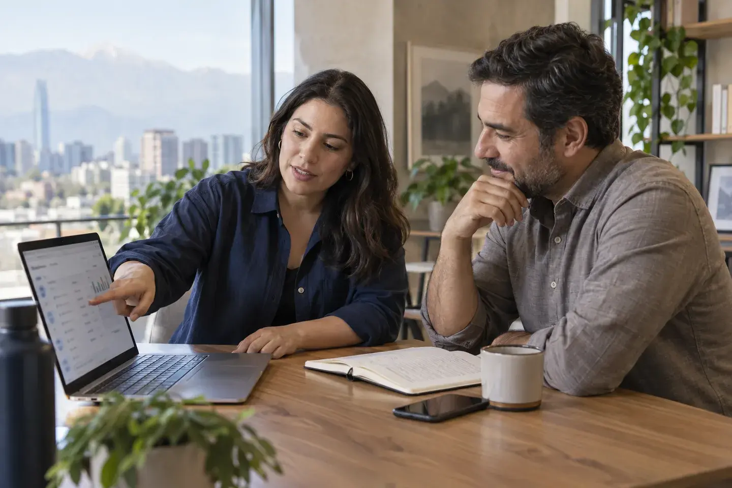 Dos personas revisan una laptop en una oficina.